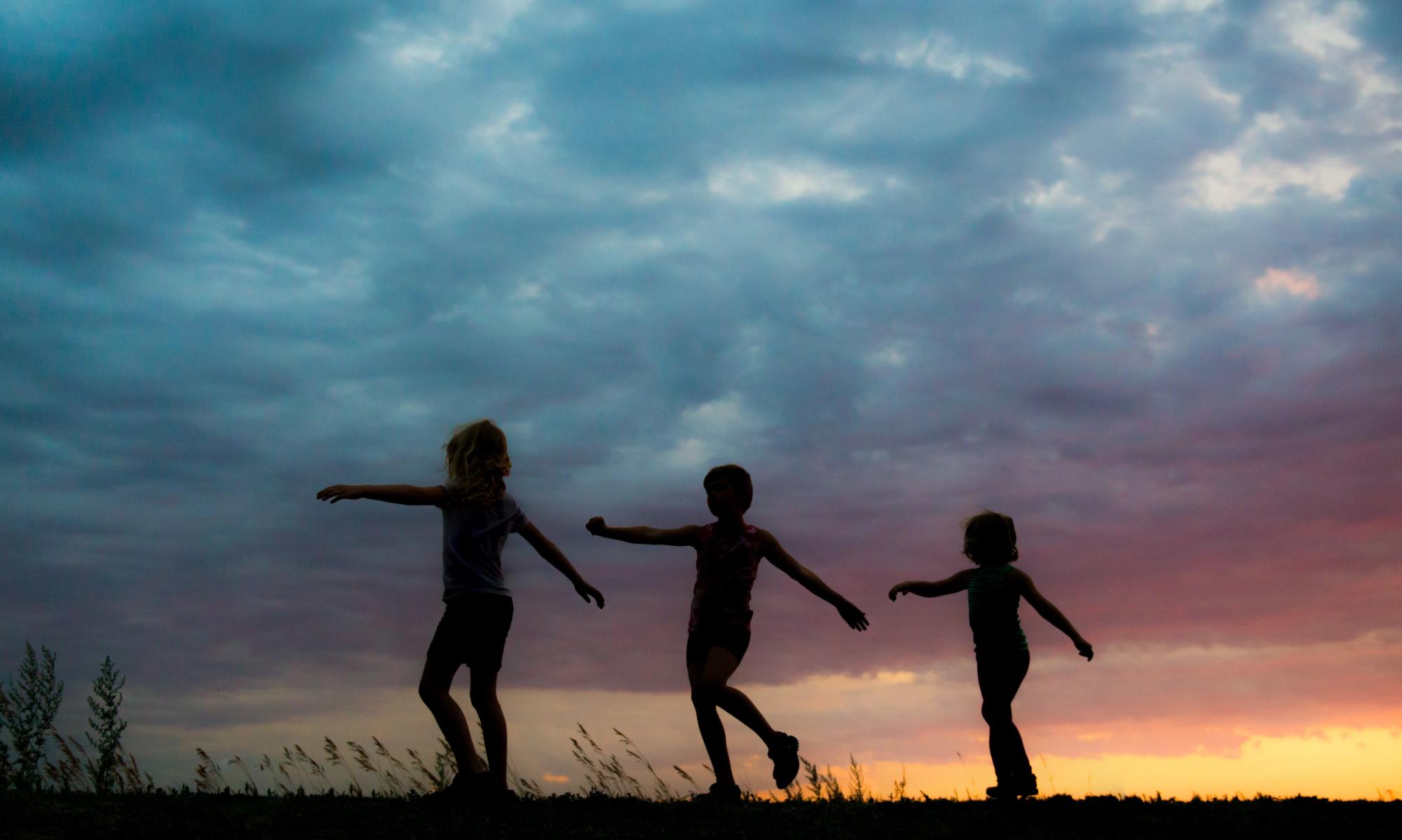 Three people sillhouted at sunset walking outdoors