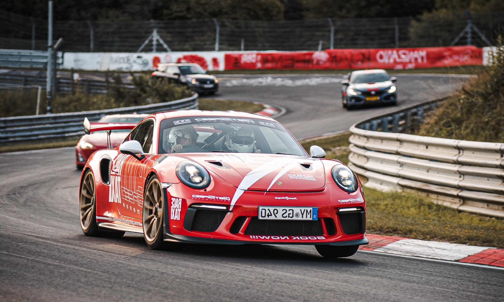 A red car at the front of the pack on a race track.